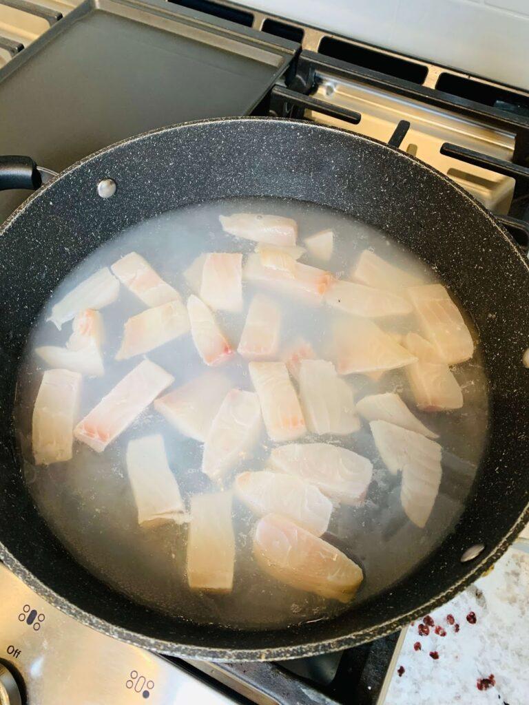 8 Easy Steps to Make the Best Tilapia Fish Ball Recipe at Home Tilapia fish ball recipe step showing raw tilapia pieces being boiled in a pot to prepare the fish for mixing.