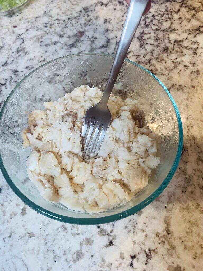 8 Easy Steps to Make the Best Tilapia Fish Ball Recipe at Home Tilapia fish ball recipe step showing cooked tilapia being mashed with a fork until fine and flaky for mixing.