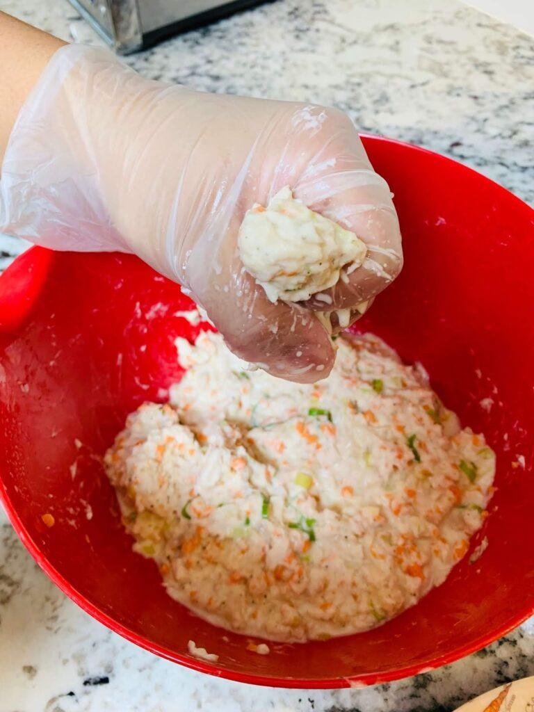 8 Easy Steps to Make the Best Tilapia Fish Ball Recipe at Home Tilapia fish ball recipe step showing the mixture being shaped into small round balls by hand using disposable gloves.