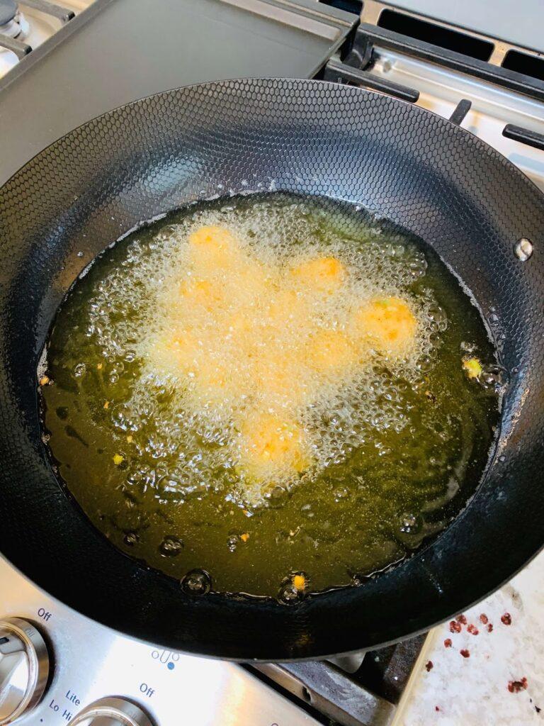 8 Easy Steps to Make the Best Tilapia Fish Ball Recipe at Home Tilapia fish ball recipe step showing the mixture being dropped into hot oil and deep fried until golden brown and crispy.