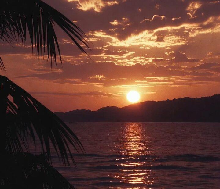 A visual representation of the word Awesome in Tagalog featuring a sunset over a tropical horizon.