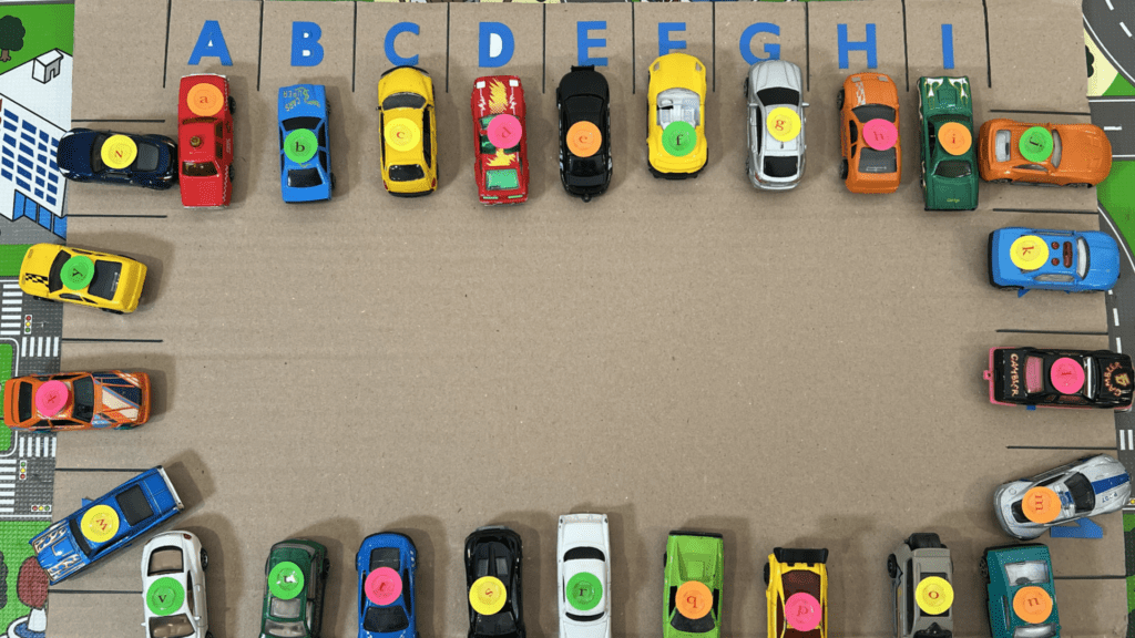 Alphabet Car Parking Game for Early Readers DIY cardboard alphabet parking lot game showing toy cars with lowercase letter stickers matching uppercase letters in parking stalls